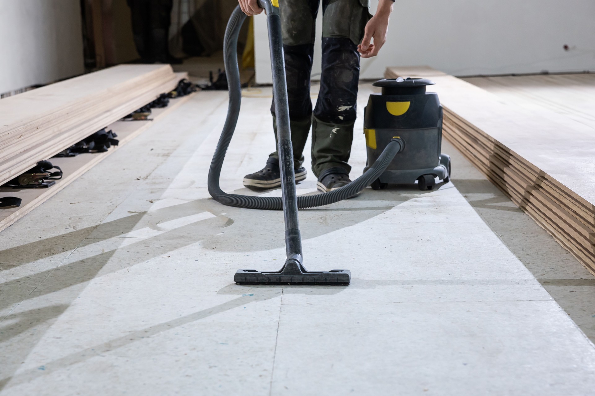 Worker Prepares Floor for Wooden Floorboard Installation Indoors